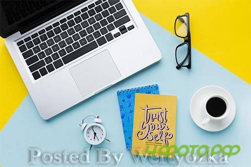 Top view of desk with laptop and clock
